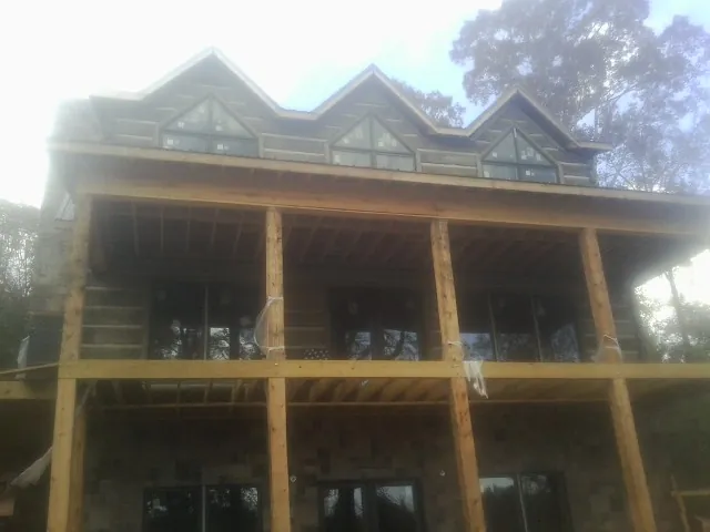 Dormers and porch framing on a large log home under construction — Roof Coating work by our crew in Cedar Hill