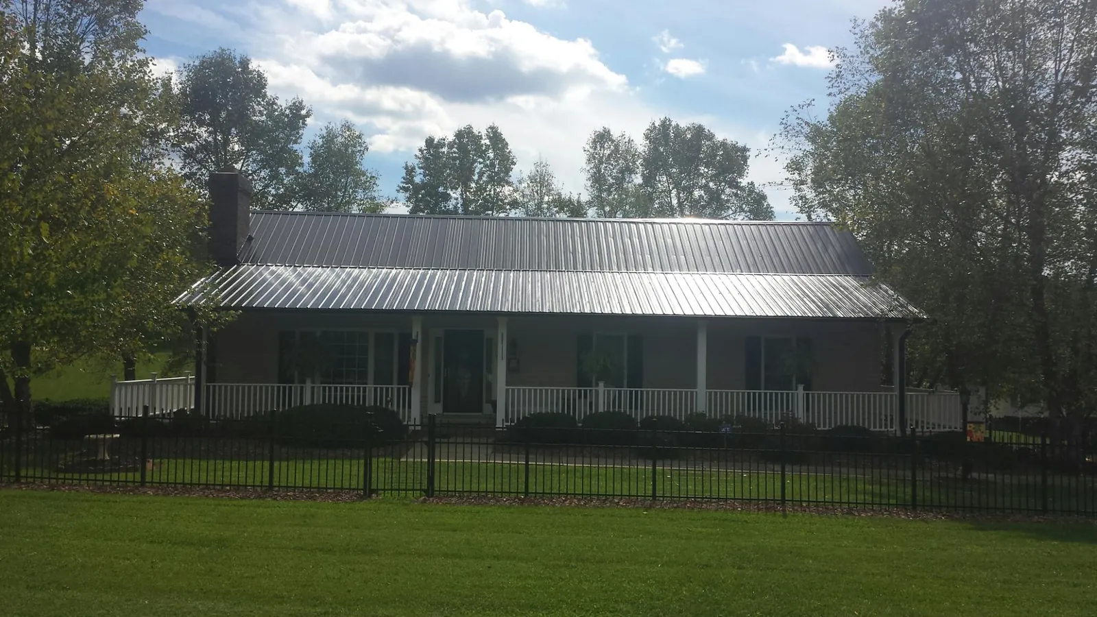Gray metal roof on a brick ranch with a full width front porch — Gutter Guard Installation work by our crew in Cedar Hill