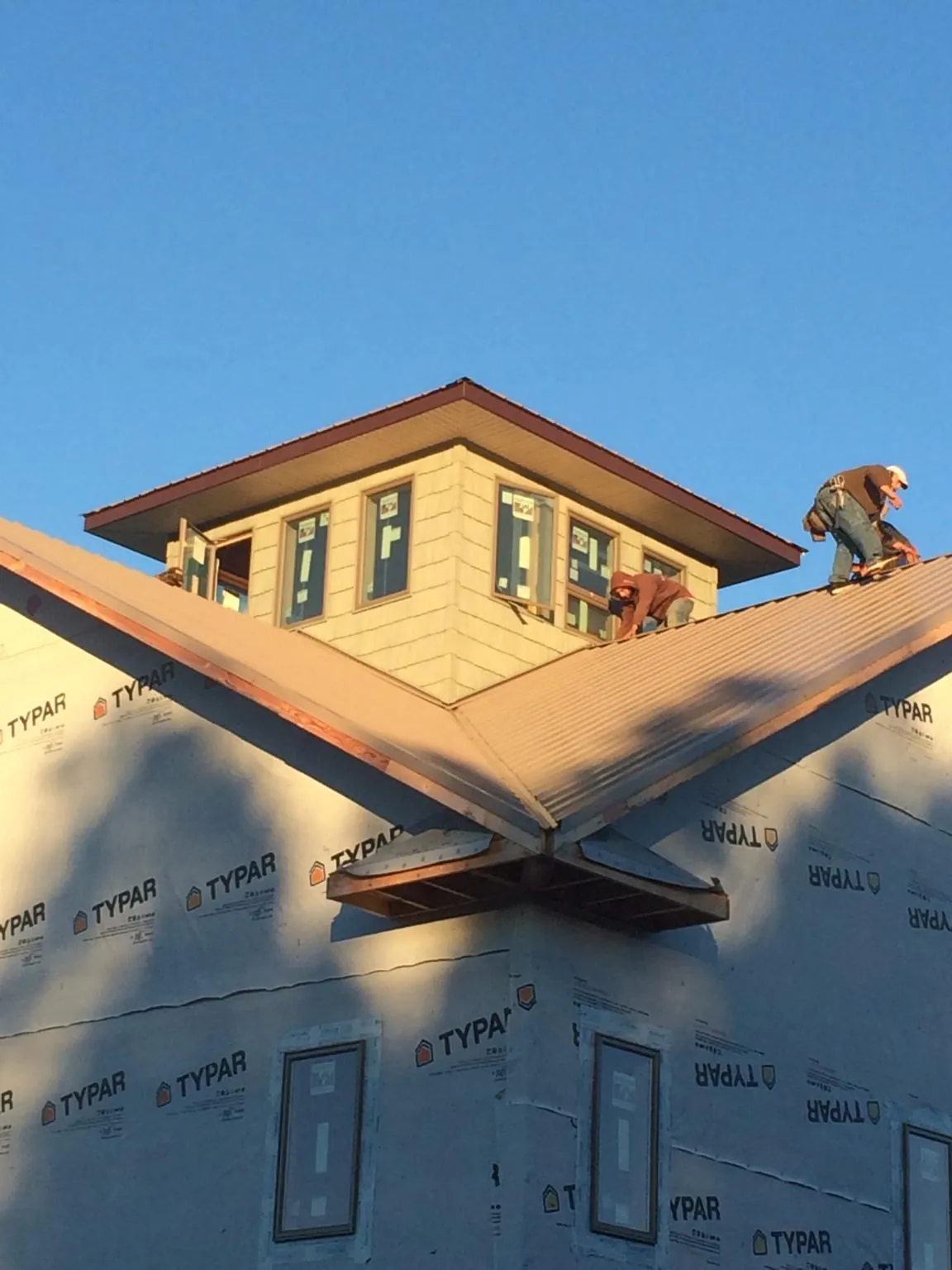 Roofers working around a rooftop cupola on a new metal roof at sunset — Roof Waterproofing in Cedar Hill by Roofing Brothers